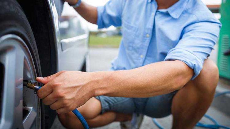 Man putting air in a car tire.