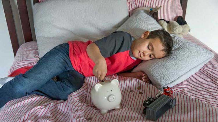 Woman with bills, laptop and calculator in front of her and adding money in a piggy bank.