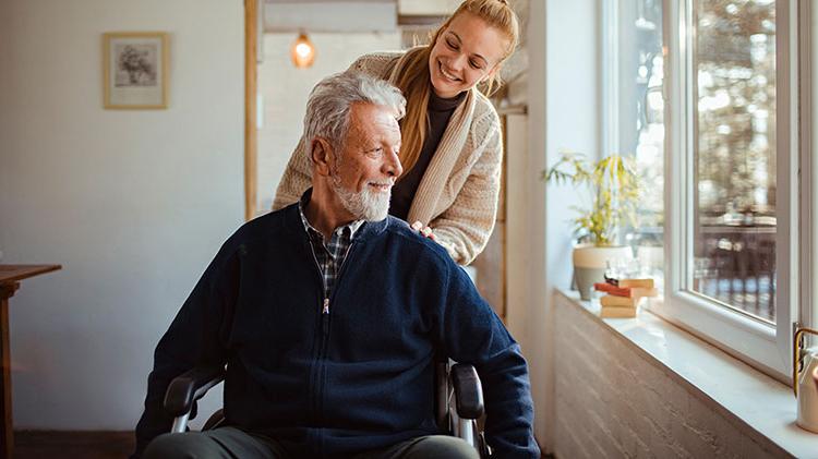 A woman pushing an older man in a wheelchair.