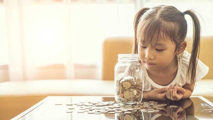 Young girl looking into jar of coins.